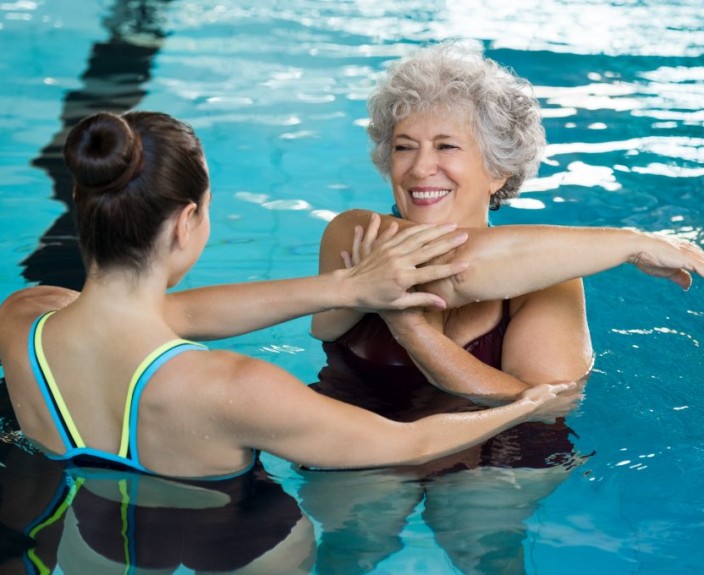 young-trainer-helping-senior-woman-aqua-aerobics-1024x680.jpg